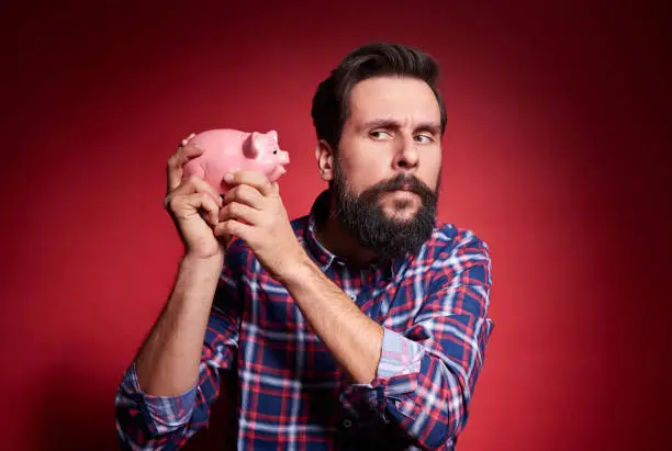 Photo of Man shaking a piggy bank
