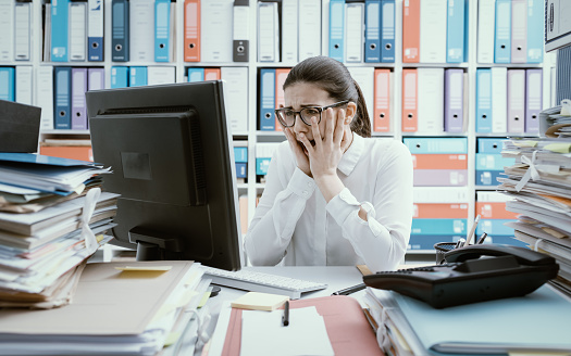 Desperate female office worker having computer problems, she is screaming and staring at the computer screen