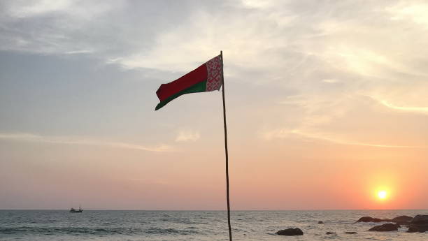 istock Belarus flag waving on ocean beach at sunset 916423190