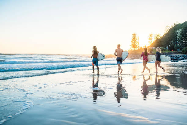 istock Friends running into the water with surfboards at sunset 916438054