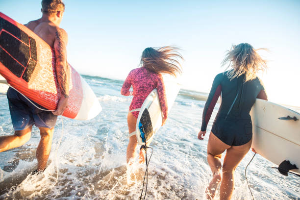 istock Friends running with surfboards into the ocean 916438064