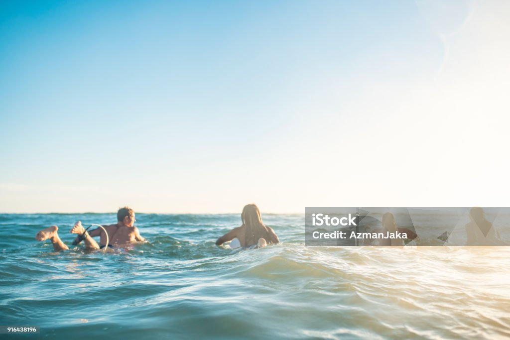 Friends preparing to surf in the ocean Surfing Stock Photo