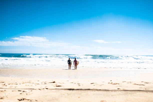 istock Friends going in the water to surf 916438236