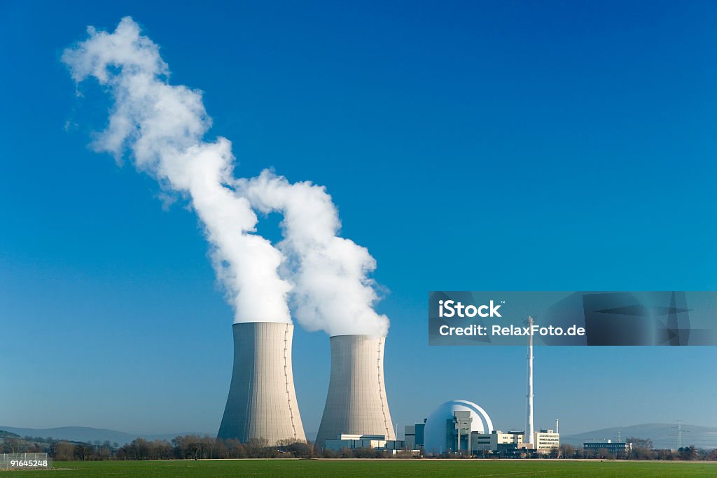Nuclear power station Grohnde with blue sky Nuclear power station with two steaming cooling towers in blue sky.  Nuclear Power Station Stock Photo