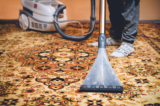 Woman cleaning carpet by washing hoover
