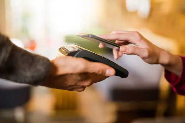 Photo of Contactless payment using a smart phone hand close up.