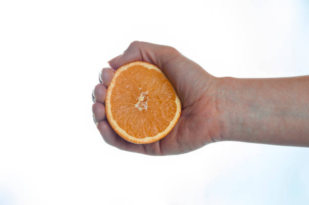 istock Female hand squeezing ripe orange 916461396