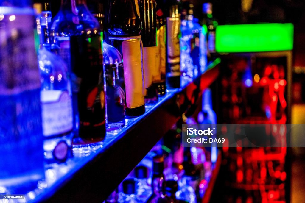 raw of bottles in a Bar Bottles on a shelf, lightened up. spirituous beverages at a bar. Bar Counter Stock Photo