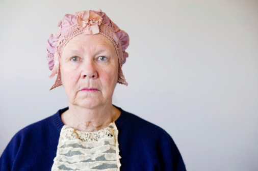 Distrustful senior woman wearing weird tinfoil hat.