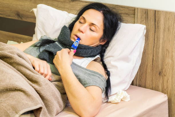 istock Sick woman keeping thermometer in mouth 916471608