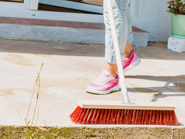 istock Woman using broom to clean up backyard patio 916475142