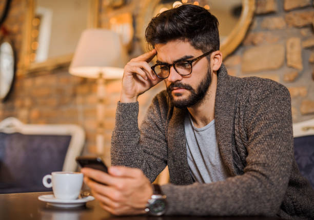istock Serious young man studying from a phone in a coffee shop. 916475230