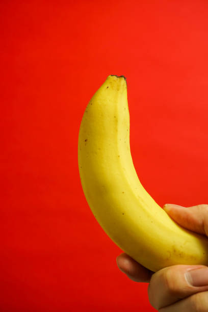 istock yellow banana, red background 916476048
