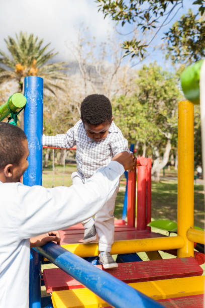 istock Father helps his son walk across a bridge on a jungle gym. 916479052