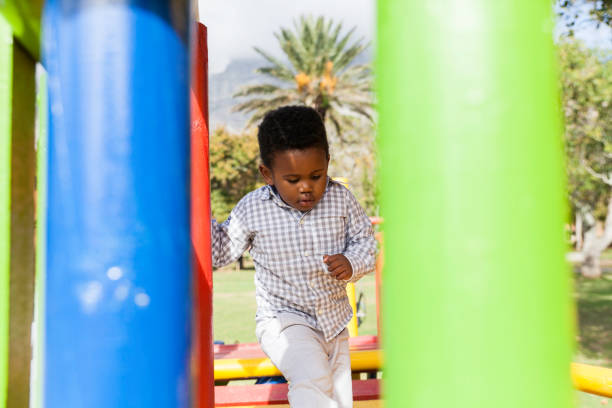 African child walking along a bridge on a jungle gym in the park.