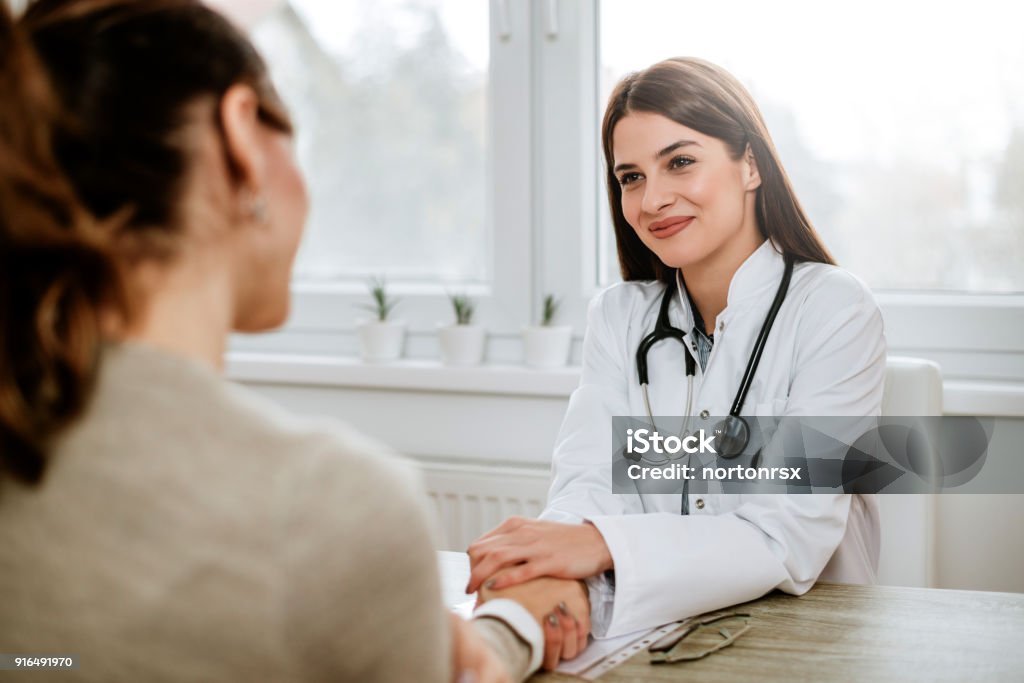 Freundliche Ärztin mit weiblichen Patienten Hand für Ermutigung und Empathie. - Lizenzfrei Arzt Stock-Foto