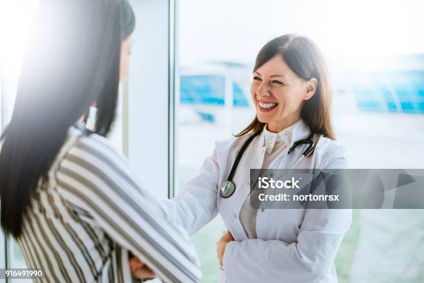Cheerful Doctor Talking With Her Patient Near Window Stock Photo - Download Image Now