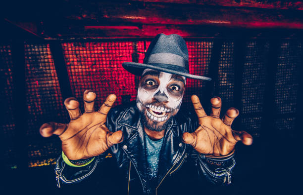 Spooky skeleton man having fun celebrating Halloween Portrait of young man disguised as scary skeleton skull having fun at Halloween party face paint halloween adult men stock pictures, royalty-free photos & images