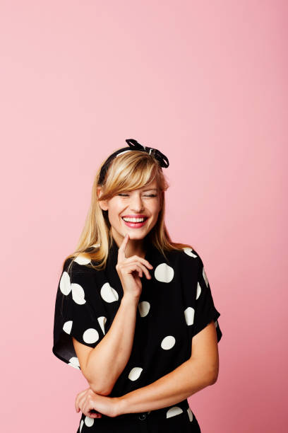 Laughing young woman in spotted dress, studio