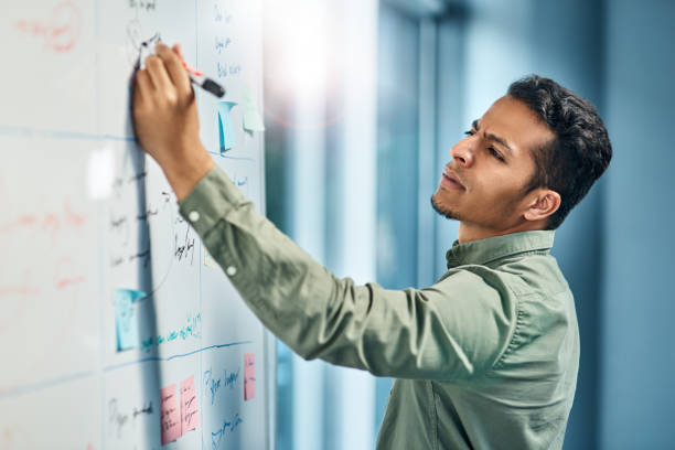 you can always find him hard at work - writing whiteboard men businessman imagens e fotografias de stock