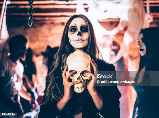 Photo libre de droit de Jeune Femme Avec Un Crâne Tenue Maquillage Squelette À La Fête Dhalloween banque d'images et plus d'images libres de droit de Halloween