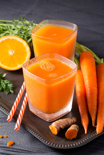 Organic Carrot Juice Two glasses of fresh organic carrot-orange juice with turmeric root carrot juice stock pictures, royalty-free photos & images
