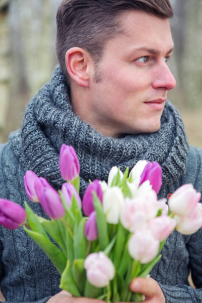 istock handsome blond man outdoors with tulips 916497656