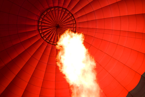 A huge flame in the foreground of the interior of a hot air balloon