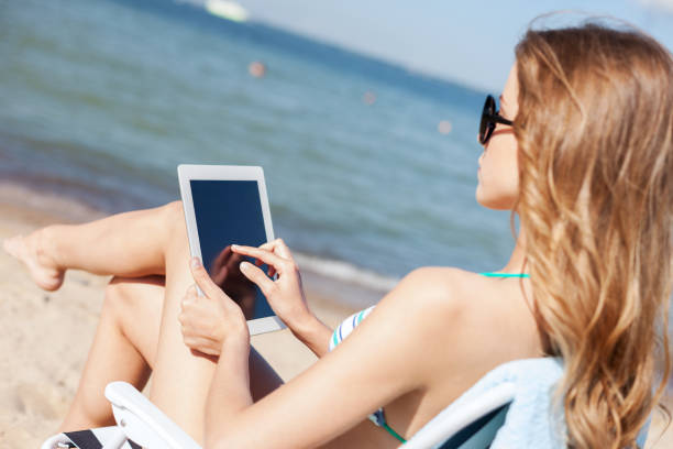 istock girl looking at tablet pc on the beach 916515536