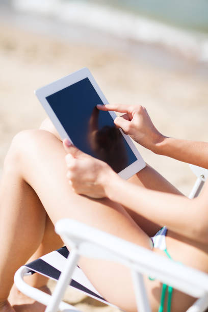 istock girl looking at tablet pc on the beach 916515730