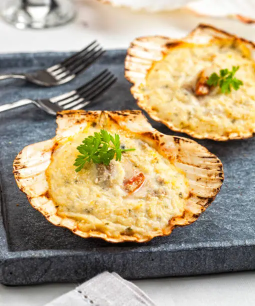 Gratinated scallops served on a stone tray.