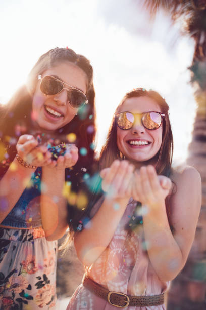 Fashionable teenage best friends having fun celebrating with confetti at summer beach party