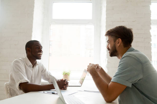 istock African-american and caucasian businessmen talking laughing having fun at work 916520104