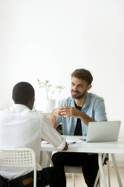 Multiracial colleagues working together talking in office teamwork, vertical view