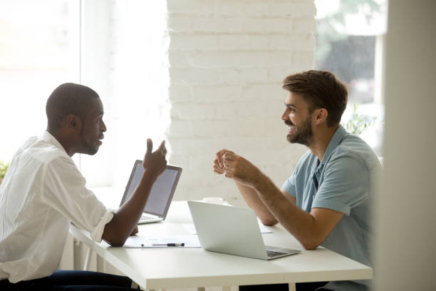istock Diverse friendly colleagues discussing new interesting idea talking at workplace 916520160