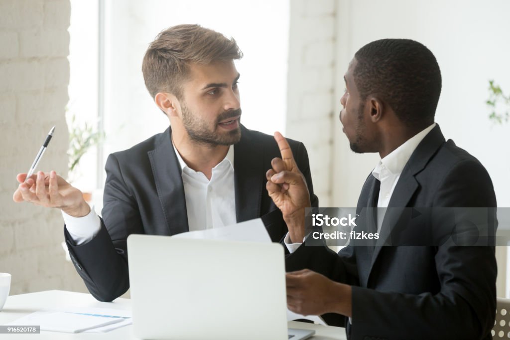 African client having claims about document disagreeing with caucasian partner African black client having claims about business document disagreeing with caucasian partner, stressed diverse businessmen arguing in office disgruntled by bad contract or obligations noncompliance Conflict Stock Photo
