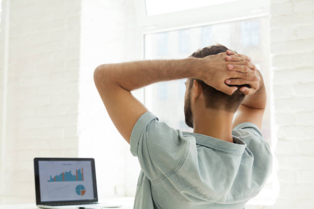 Rear view at man looking at statistics on laptop screen