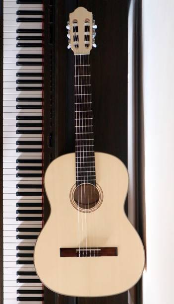 istock Acoustic classic guitar next to the piano keyboard 916526316