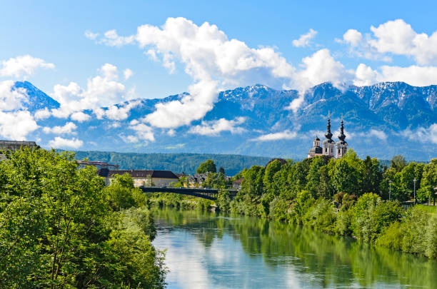 The Alps in Villach - mountain view with the clouds The Alps in Villach - mountain range in the clouds with a small chapel on the bank of the river villach stock pictures, royalty-free photos & images