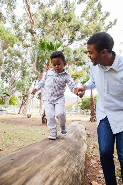 istock Dad guiding his little boy along a log. 916541944