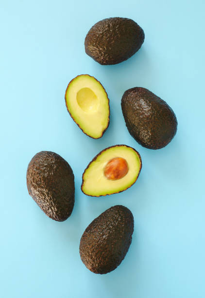 istock Avocado halves and whole on a blue speckle, top viev. 916564896