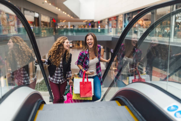 Girls having fun in the shopping center Young women in the shopping mall using the escalator to move on the upper floor escalator stock pictures, royalty-free photos & images