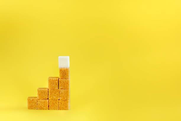 istock Sugar cubes on a yellow background - concept of growth. Copy space 916568158