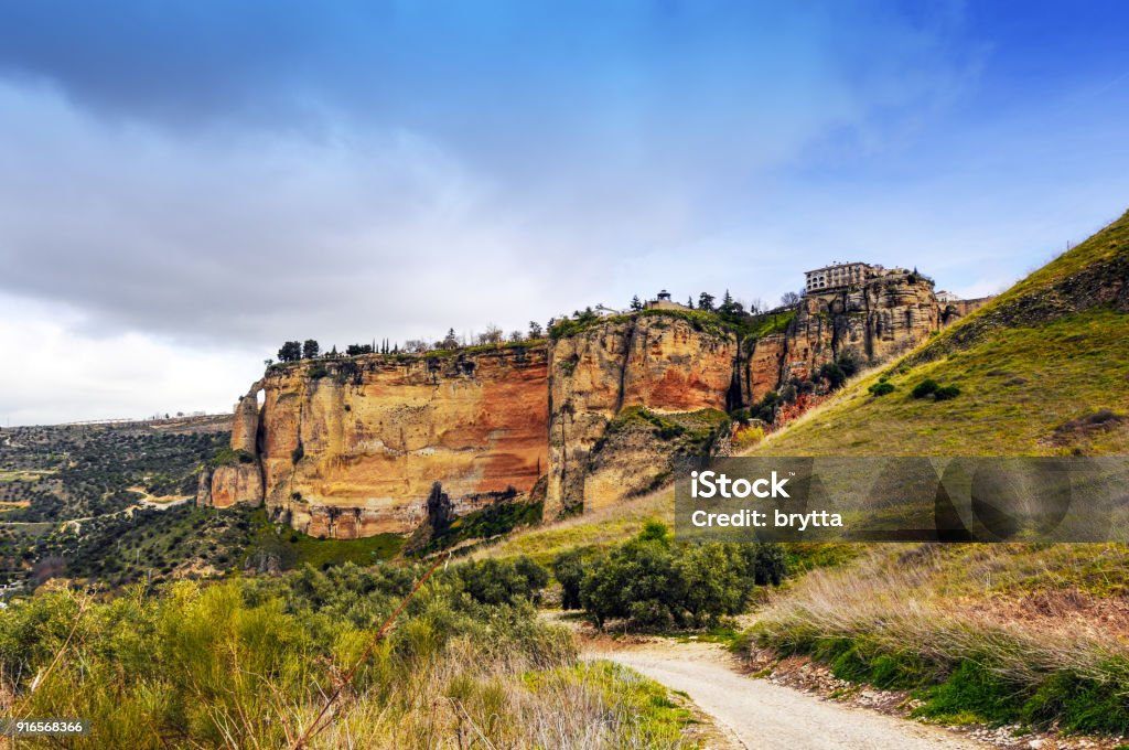 View at the landscape and the Parador National in  Ronda,Andalusia,Spain Ronda is a town in the Malaga province of Andalusia. The Parador Nacional can be seen on top of the cliff . Footpath Stock Photo