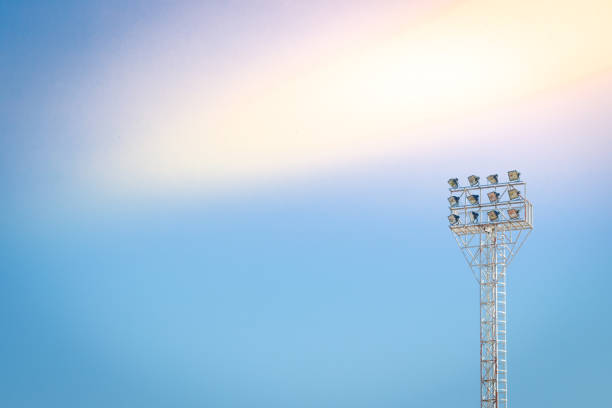 освещение башни стадиона на фоне неба - floodlight blue sky day стоковые фото и изображения