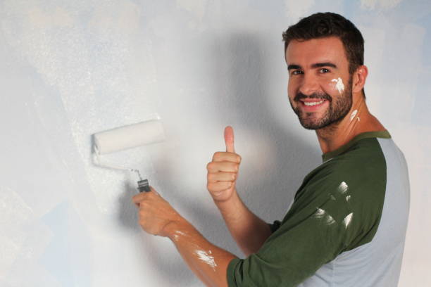 istock Joyful male painting a wall with roller 916574784