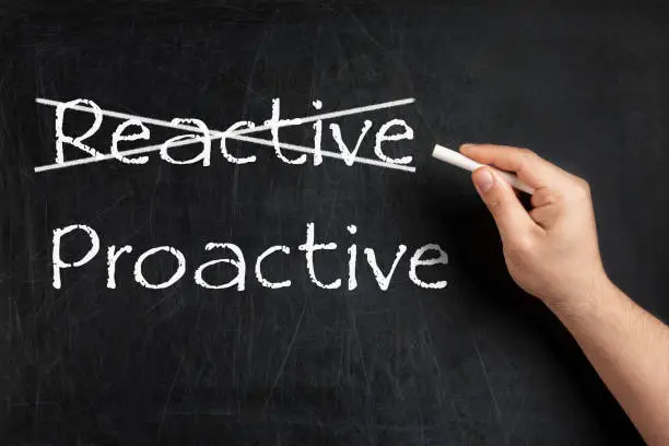 Being Proactive not Reactive crossed on blackboard or chalkboard