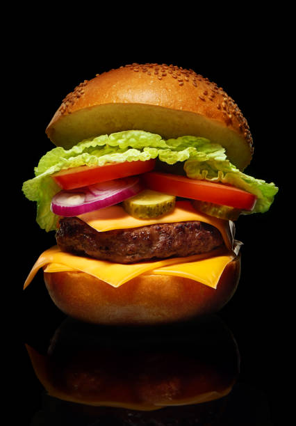 istock Hamburger with cheese, pickles, tomato, onions, lettuce on black 916579996