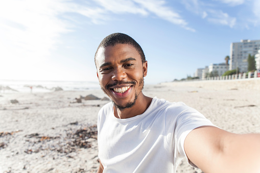 African man taking a selfie on the beach.