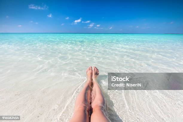 Vacation On Tropical Beach In Maldives Womans Legs In The Clear Ocean Stock Photo - Download Image Now
